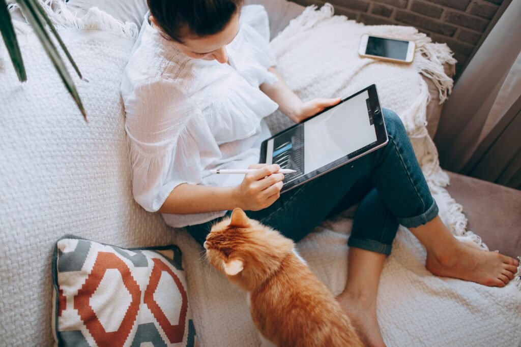 Woman working remotely on a tablet at home with a cat nearby, exploring ServiceNow salaries across the UK
