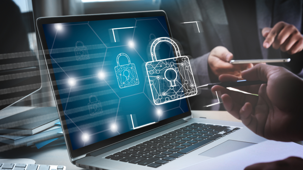 Laptop screen showing glowing padlock icons on a linked network diagram, with a person using a smartphone beside it